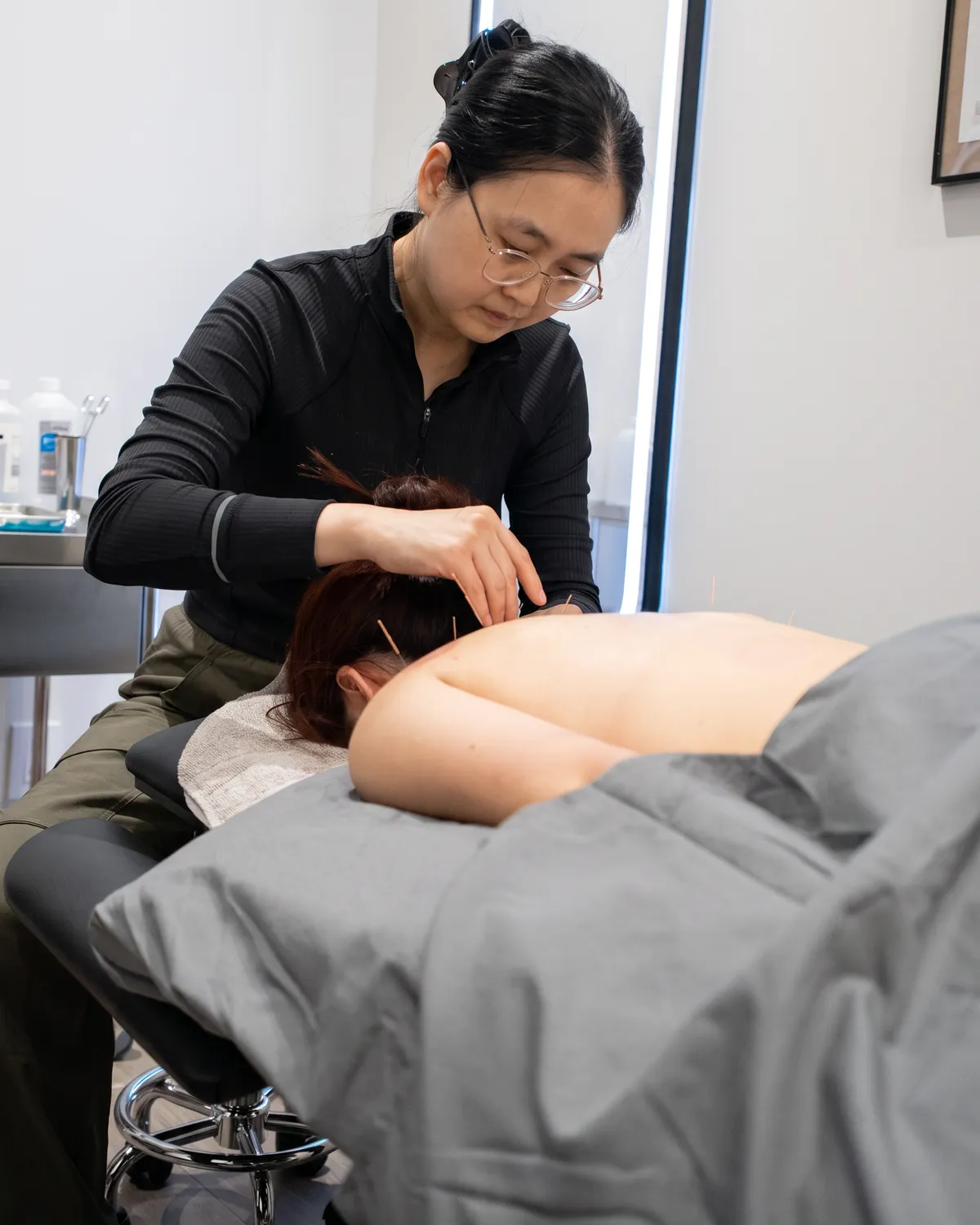A Registered Acupuncturist placing needles along a patient's upper back at Fittopia Wellness Studio.