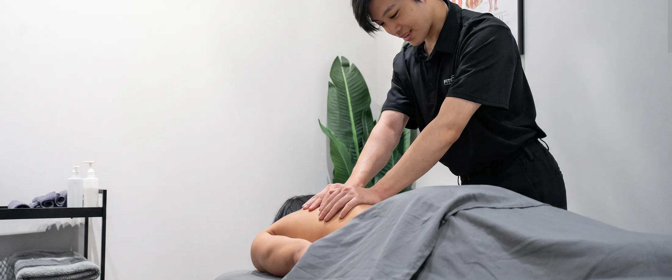 A registered massage therapist treating a patient in a treatment room at the Fittopia Health Care clinic.