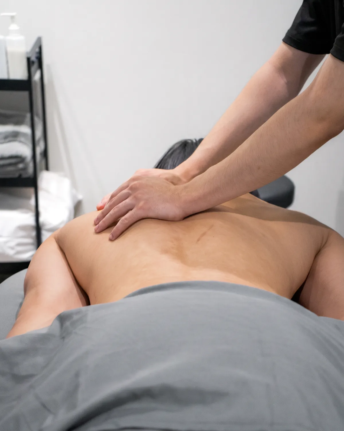 A Registered Massage Therapist's hands working along a patient's back during treatment.